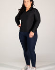 Woman wearing a black long-sleeve top and navy leggings on a white background