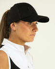 Woman wearing a black cap and white shirt against a plain background